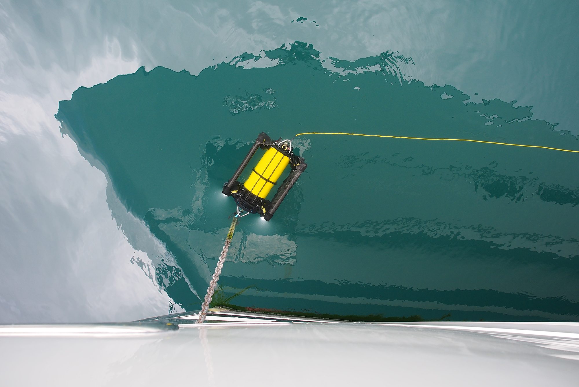 Boxfish ROV pictured in the water with a reflection of a yacht